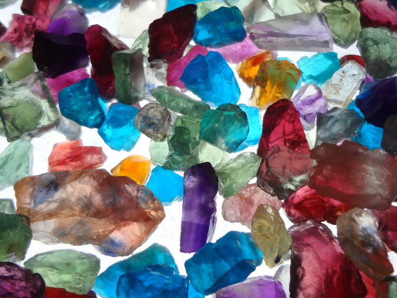 Potpourri of mixed colourful rough gemstones, purple, blue, yellow, green, orange, red and all colors. 